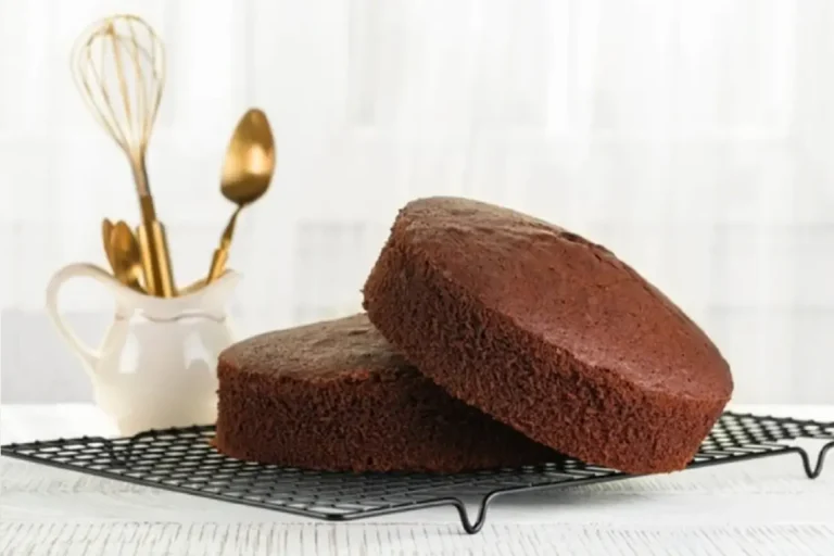 A golden brown Bundt cake adorned with a light dusting of powdered sugar on top, placed on a rustic wooden table