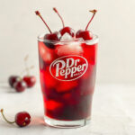 A finished Cherry Dirty Dr Pepper in a glass, showcasing the vibrant red color and fizz. — dirty cherry dr pepper